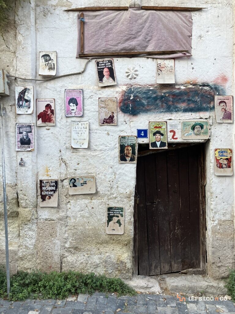Weathered wooden door and framed photos on a stone wall in Cappadocia